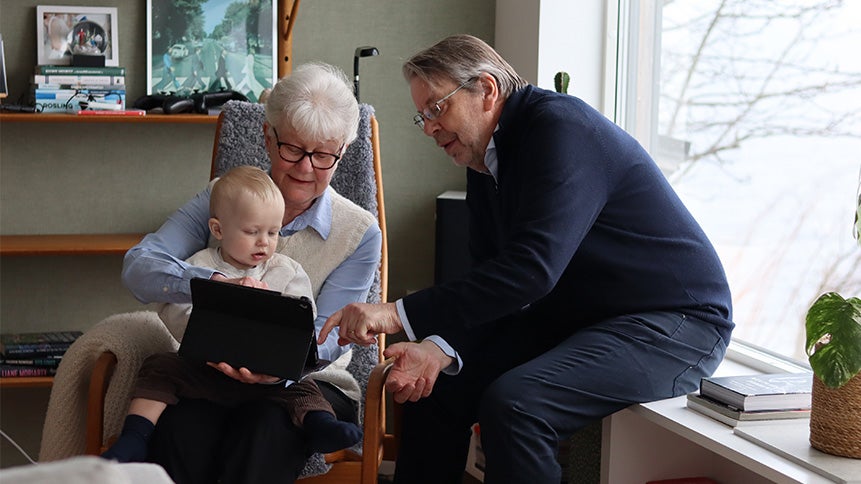 Kvinna och man med barn tittar på läsplatta i vardagsrummet