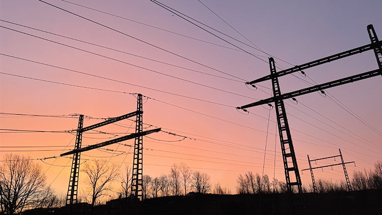 Rosa himmel i solnedgång över flera elledningar i svart.