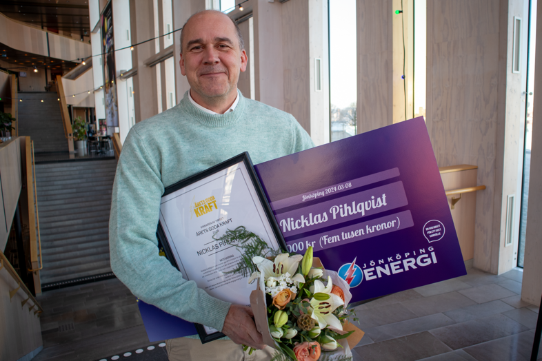 Nicklas Pihlqvist, vinnare av priset Årets goda kraft står slatt upp med diplom, presentkort och en bukett blommor.