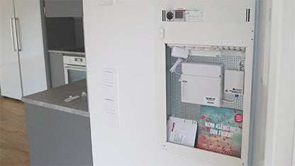 Öppet mediaskåp i modern bostad med installerad fibernod och informationsmaterial från Jönköping Energi om igångsättning av fiberanslutning.