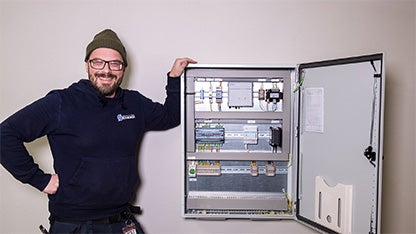 Fjärrvärmetekniker står bredvid en fjärrvärmecentral