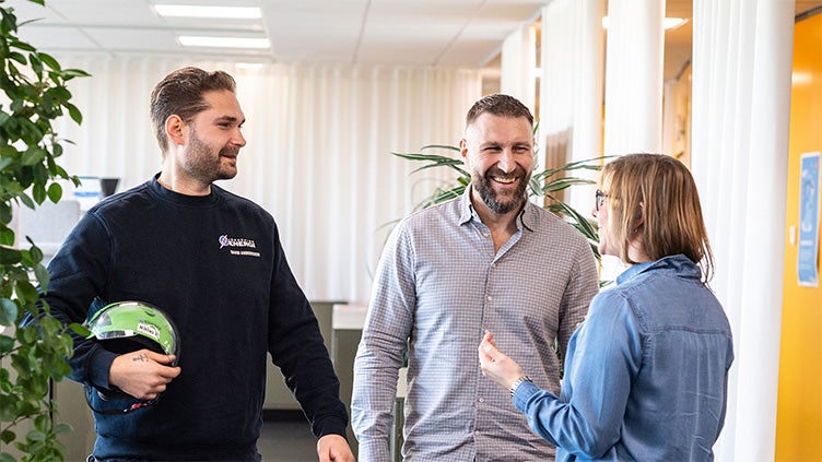 Tre medarbetare står och pratar i korridoren.