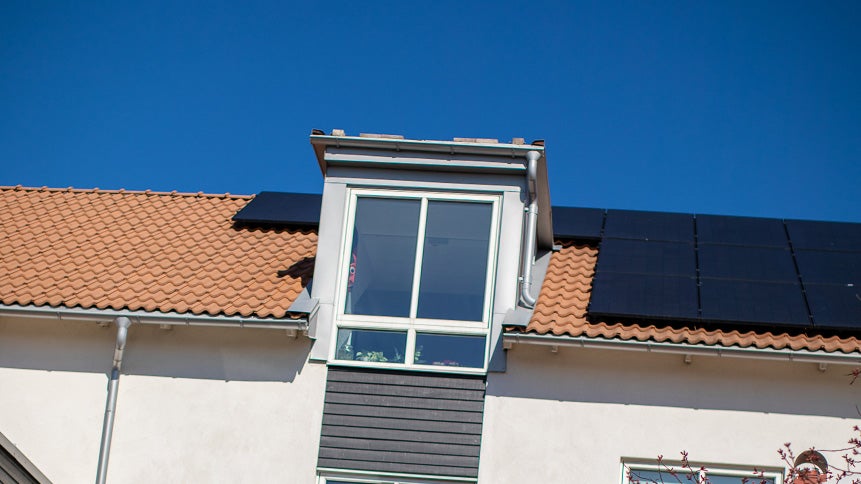 Orange tak på ett hus med takfönster och svarta solceller.