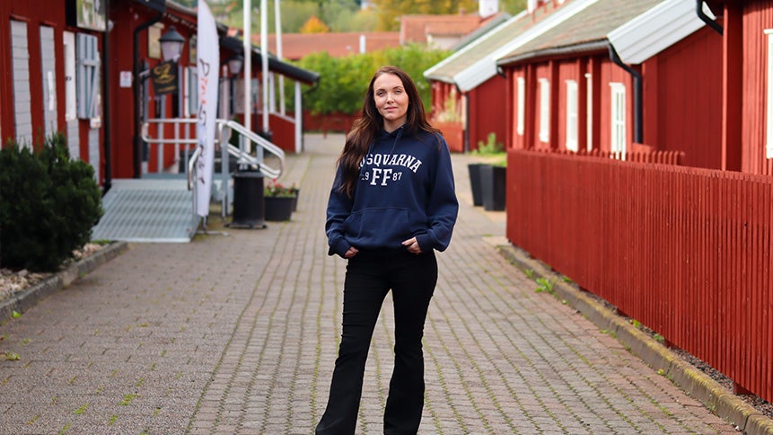 Bild på Zandra Zaar när hon står på en kullerstensgata emellan röda stugor.